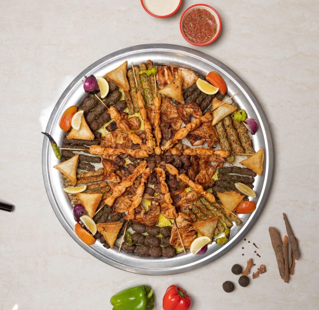Delicious Middle Eastern kebab platter with various meats and fresh vegetables, top view.